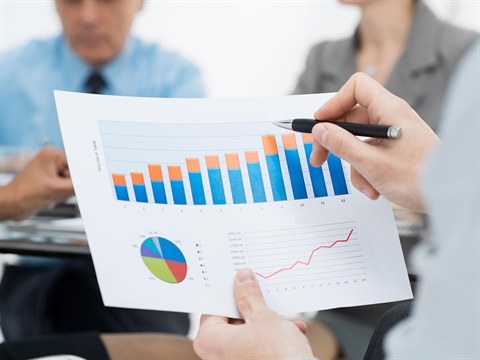 Man-holds-print-out-of-business-graph-and-tables-at-a-conference-table.jpg