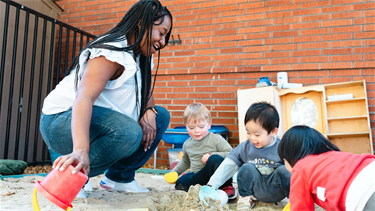 Teacher playing in the sand with children