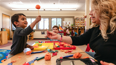 Child at a desk doing an activity with a teacher