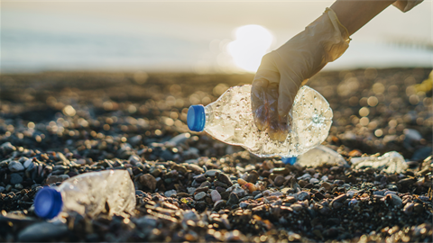 Gloved hand picking up bottles on beach