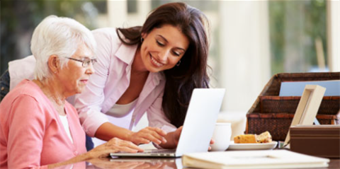 Woman assisting elderly woman with computer