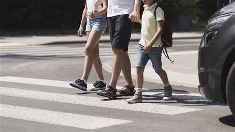 Father-walks-two-children-across-the-street-in-front-of-a-stopped-vehicle.jpg