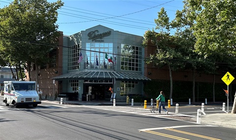 A pedestrian pushes a shopping cart across Menlo Avenue with new safety improvements