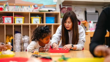 Child at BHCDC sits with teacher