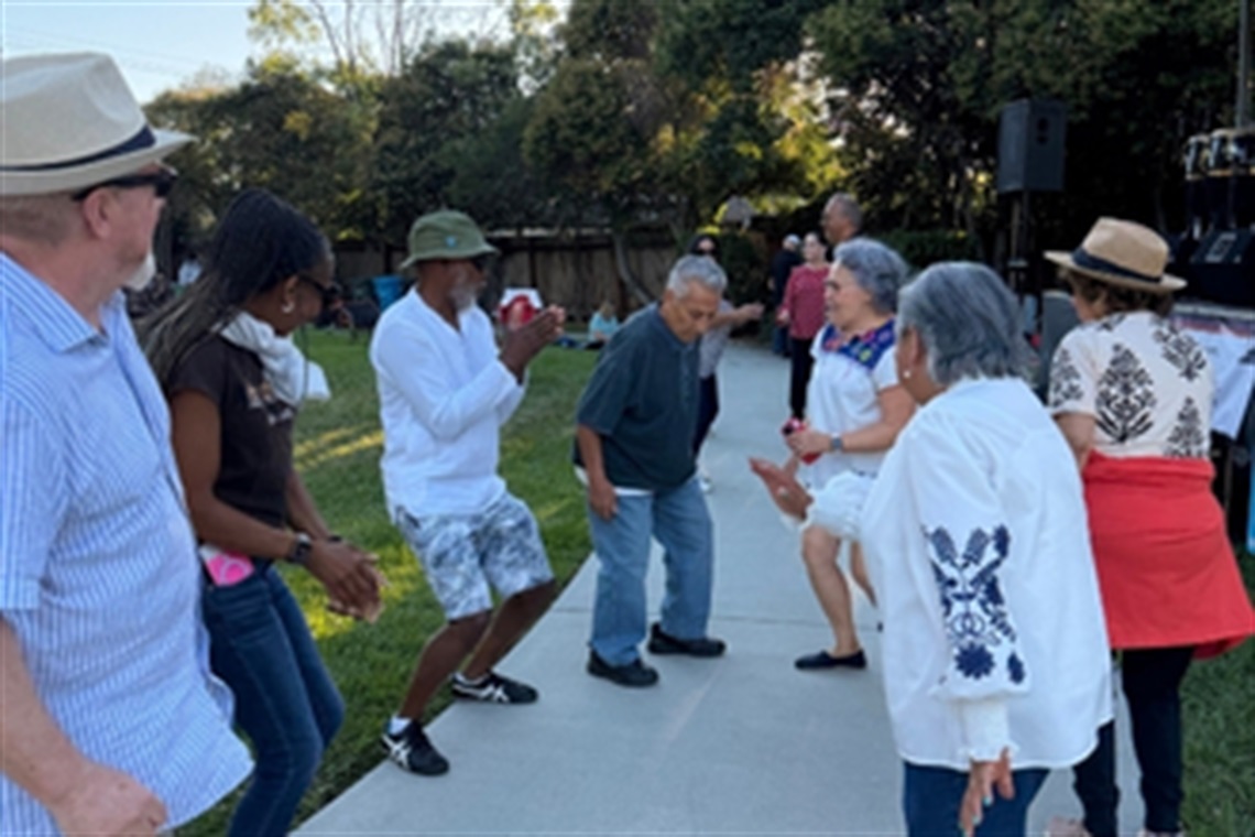 Community members dance together in a park